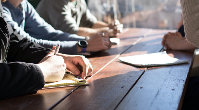 People taking notes at a bench