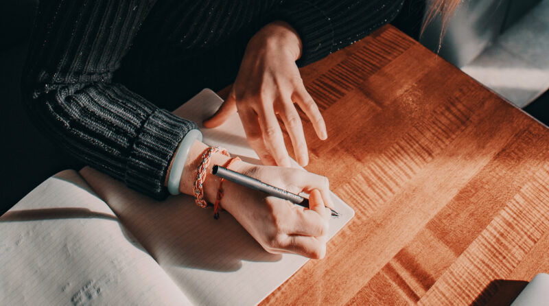 Hands writing in notebook