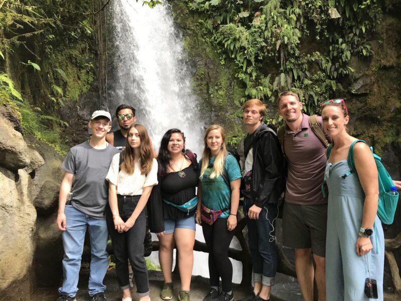 A group of students in front of a waterfall.